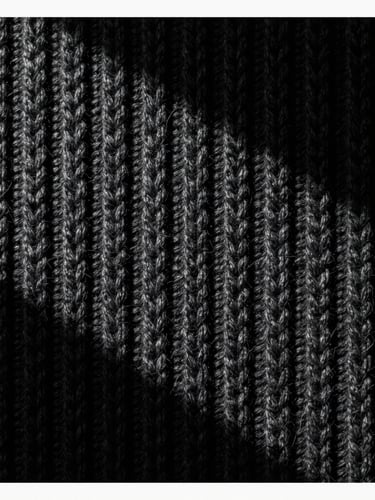 Close-up of heavy-gauge charcoal textile weave showing intricate structural knit, dramatic high-contrast side-lighting, deep obsidian tones, sharp focus, medium format film