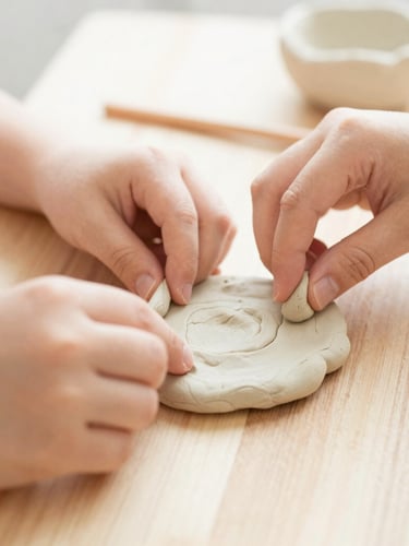 Macro close-up of parent and child hands shaping soft air-dry clay together on a wooden table, soft overexposed photography, natural bright daylight, warm cream tones, shallow depth of field, 35mm