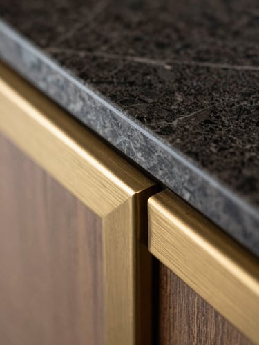 Macro close-up of a material junction, dark marble countertop meeting a brushed brass gold metal trim, soft side lighting, sharp focus