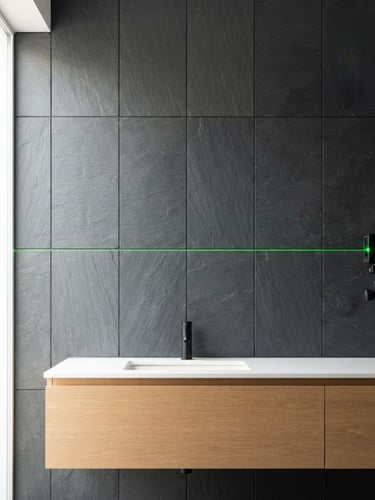 Straight-on architectural shot of a modern bathroom wall, laser level casting a crisp green line across perfectly aligned slate tiles, bright natural daylight, 35mm lens