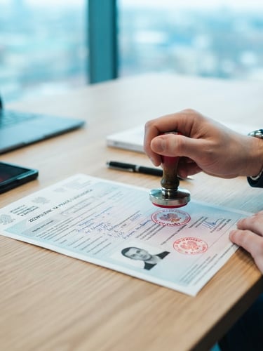 Close-up of official Polish work permit documents being stamped on a modern desk, natural bright daylight with cool blue tones, professional photography