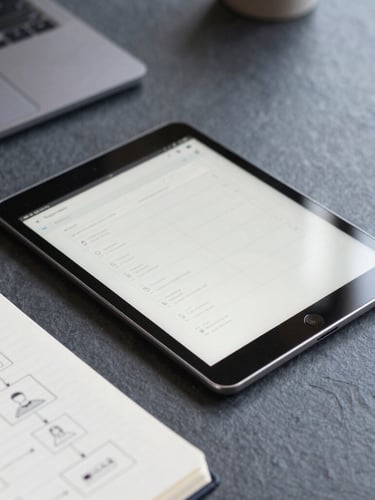 Overhead macro shot of a clean desk with a tablet displaying a wireframe interface, a notebook with pencil sketches of user flows, soft natural daylight, slate tones