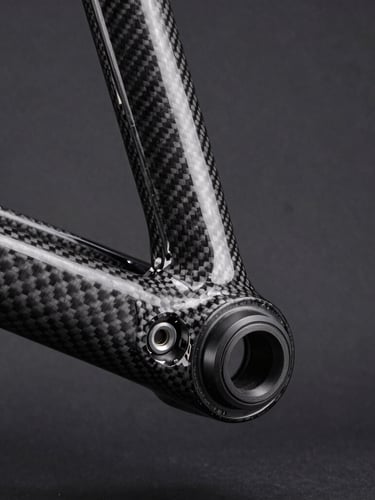 Tight macro shot of a carbon fiber bicycle frame bottom bracket, high-contrast studio lighting, deep charcoal background, sharp focus on mechanical details.