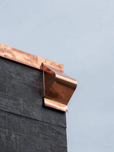 Tight architectural photo of clean copper flashing installation on a Manhattan rooftop, bright overcast daylight, steel blue sky, sharp focus