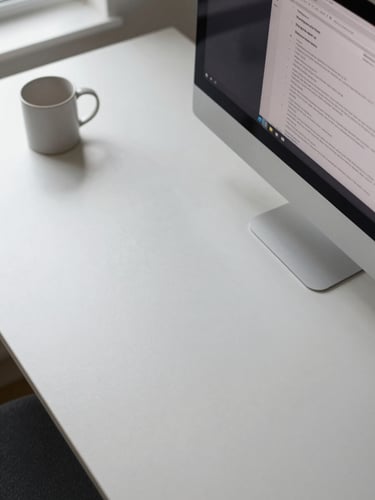 Clean overhead angle of a minimal desk surface, a monitor displaying a browser with a review page open, natural window light casting soft even illumination across the scene, a plain ceramic mug at the far corner, no clutter