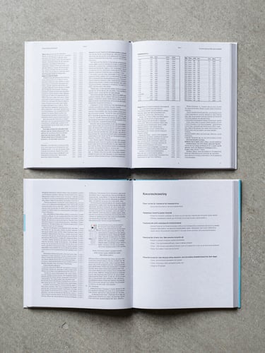 Flat lay overhead shot of an open academic journal spread on a clean concrete surface, dense typeset columns and data tables visible, a printed manuscript with reviewer annotations beside it, controlled north-facing daylight, minimal shadows, high contrast on text surfaces