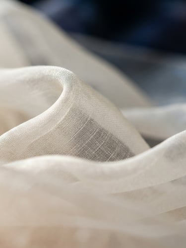 Macro close-up of luxurious Turkish organza fabric in ivory, showing delicate weave and soft drape under diffused side-lighting, shallow depth of field.
