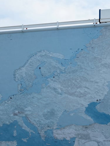 A clean, high-contrast graphic map showing maritime shipping routes from the East Coast of the United States to Europe and the Middle East, cool blue tones.