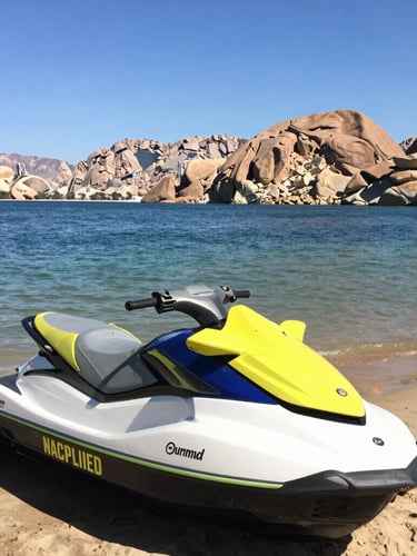Three jet skis parked on a sandy beach near water.