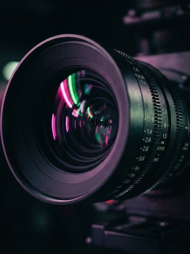 Extreme close-up of a high-end cinema camera lens reflecting vibrant pink and electric green neon studio lights, shallow depth of field, moody dark background