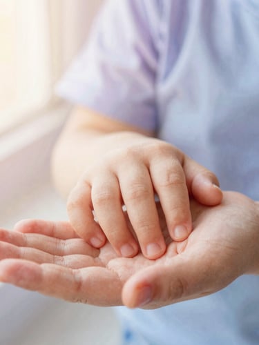 Intimate macro shot of a child's small hand resting in a parent's open palm, soft watercolor tones of lilac and blue in the background, warm diffused light.