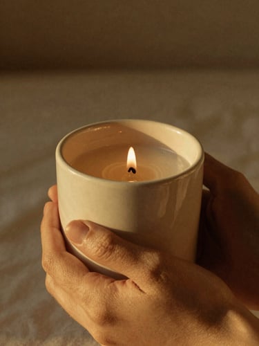 Intimate close-up of hands holding a warm ceramic candle, soft golden hour light, sepia tones, shallow depth of field, 35mm film grain