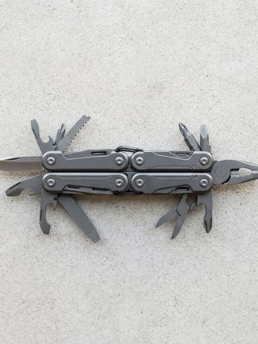 Centered straight-on shot of a high-quality anodized aluminum multi-tool on a clean concrete surface, bright natural daylight, crisp neutral tones, sharp focus, 50mm lens