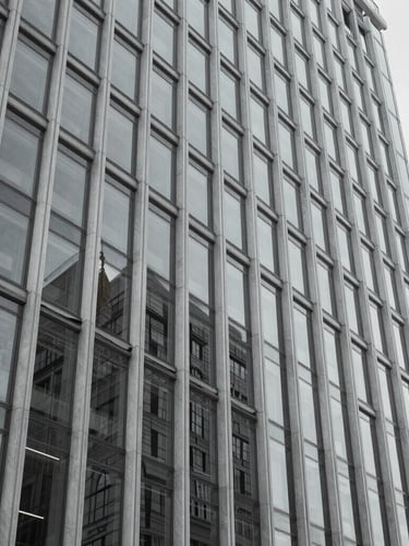 Wide-angle desaturated photograph of a modern glass-and-steel civic building facade, sharp focus, cool-toned daylight, architectural depth of field