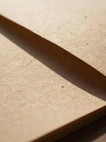 Extreme close-up of heavy textured handmade paper stock casting a deep shadow under harsh desert sunlight