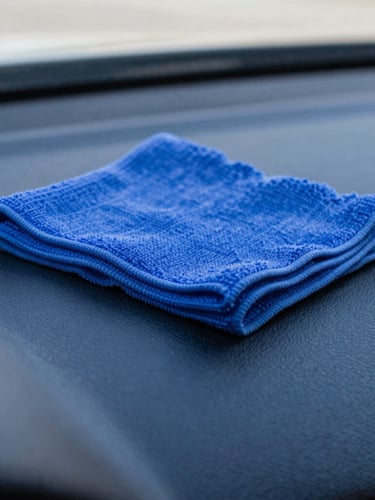 Close-up macro shot of a clean microfiber cloth wiping a pristine dashboard, bright natural daylight, sharp reflections, high-contrast electric blue tones