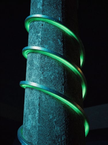 Low-angle close-up of a 3D fluid metallic sculpture wrapping around a textured concrete pillar, neon turquoise rim lighting, dark atmosphere