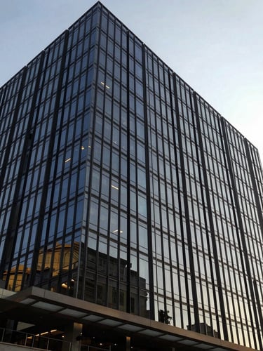 Wide-angle editorial photograph of a modern glass office building in Nairobi, bright natural morning light, architectural lines, rich navy tones, 35mm
