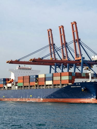 Wide-angle industrial shot of a massive container ship loading at the Port of Singapore, overcast morning light, deep blue water, towering cranes, high-visibility operations.