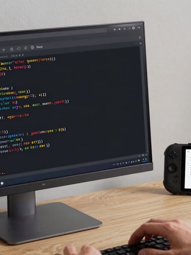 An over-the-shoulder perspective of a developer analyzing a clean Kotlin code IDE on a vertical monitor next to an Android test device showing a user flow diagram, cool studio lighting