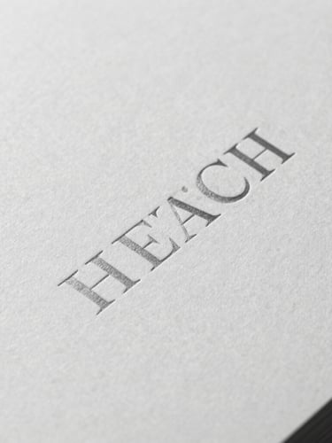 Tight macro shot of a monochrome book cover with blind-debossed serif typography, soft side shadow, premium textured paper