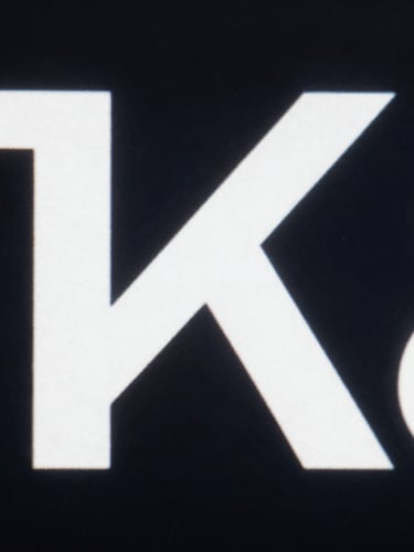Extreme close-up of a high-fidelity interface, stark white typography on dark background, sharp defined shadows, portrait orientation.