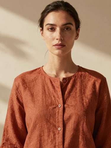 Editorial portrait of a sophisticated woman in a terracotta linen tunic, warm natural sunlight, soft directional shadows, 35mm film aesthetic