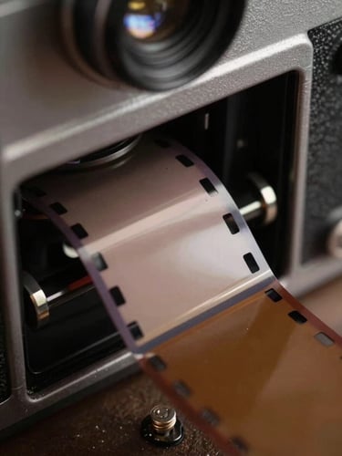 Macro close-up of physical film stock running through a camera gate, harsh set-light spill, dramatic shadows.