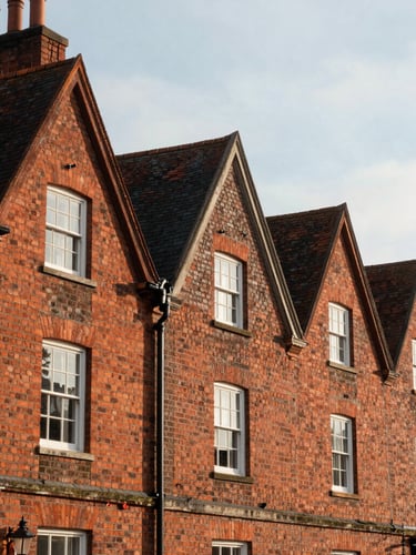 A high-contrast architectural crop of historic red brick townhouses on Legh Road in Knutsford, soft natural afternoon light, elegant slate roofs