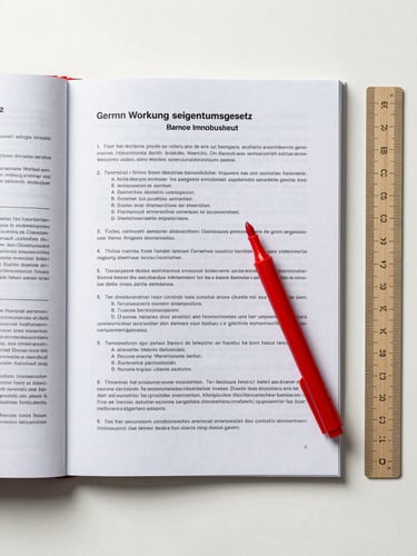 Close overhead flat-lay of a German Wohnungseigentumsgesetz document open to a dense clause page, a red ink marker resting across the text, a ruler alongside, neutral studio lighting, no shadows, clinical white surface beneath