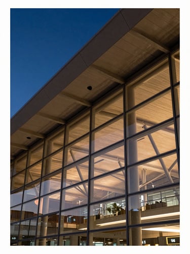 Close-up architectural detail of a modern airport terminal facade at dusk, structural steel ribs and glass panels reflecting amber light, deep blue sky beyond, no people, scale and precision foregrounded