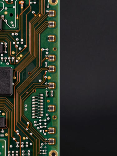 Extreme close-up of a multilayer automotive circuit board under cool studio strobes, precision-etched copper traces visible in sharp detail, dark industrial background, left-third framing with generous negative space to the right