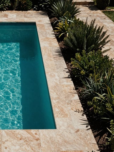 Wide environmental shot of a completed pool integrated into a Mediterranean garden terrace in Alicante, architectural geometry of the pool edge visible in the left third, natural stone coping under midday light, lush low vegetation framing the right side, cool documentary tone