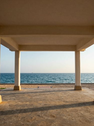 Wide-angle architectural shot of the open-air pavilion structure at Gangothri HarbourFront, showing its clean lines framing the Arabian Sea at late afternoon sun, with subtle maritime details of Puthiyappa Harbour visible.