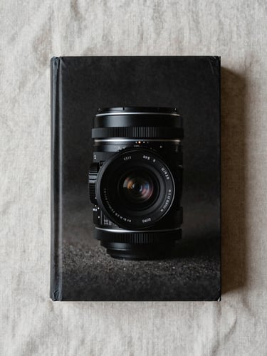 Overhead flat-lay of a thick paperback on a pale linen surface, diffused daylight, even shadows, no text visible on cover