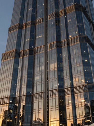 Extreme wide-angle architectural abstract of a modern Dubai skyscraper facade at twilight, deep navy steel and golden hour light reflecting off geometric glass panels, sharp clean lines, negative space on the left.