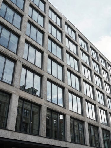 Wide cinematic shot of a modern glass and concrete A-class office building facade in Vilnius during bright diffused daylight, clean architectural lines, reflecting the sky