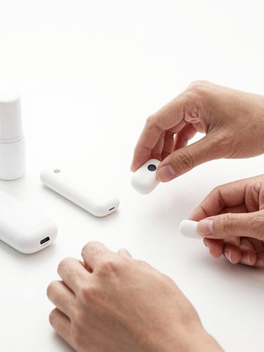 Crisp product photography, seamless white background, bright studio lighting, high contrast, sharp focus, 50mm lens, a close-up of hands meticulously arranging small, minimalist electronic gadgets and beauty products on a clean white table, emphasizing organization and attention to detail, monochrome aesthetic.