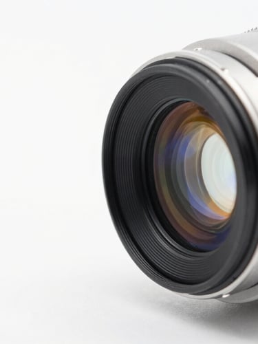 Macro shot of a high-precision optical lens catching light, clean white background with subtle blue and amber refractions, sharp focus, 50mm lens.