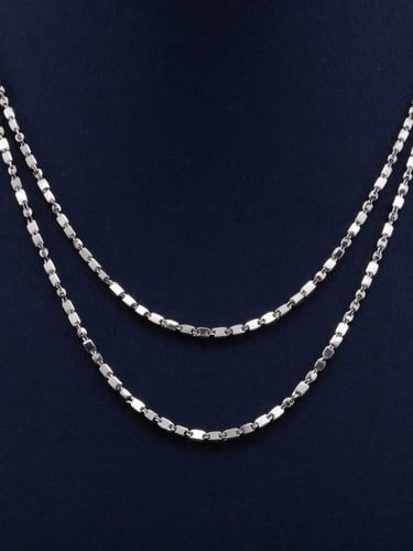 Macro photography of three layered silver necklaces on elegant neck, cool studio lighting, deep navy background, sharp metallic reflections.