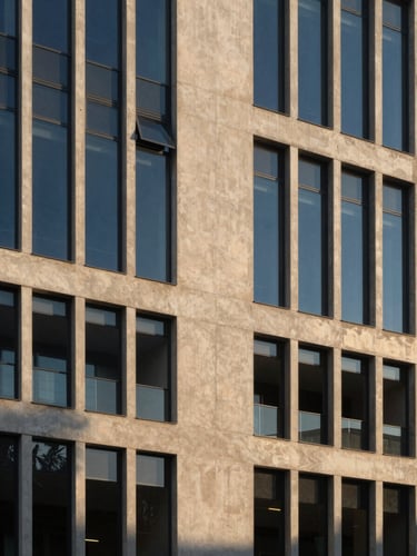 Elegant architectural photography of a contemporary concrete and glass facade in Spain, soft golden hour light, deep blue shadows, medium format editorial composition