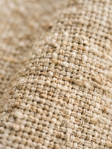 Tight macro shot of premium Belgian flax linen fabric, showing detailed tactile weave in warm oatmeal and sand tones, soft morning daylight, shallow depth of field, 35mm