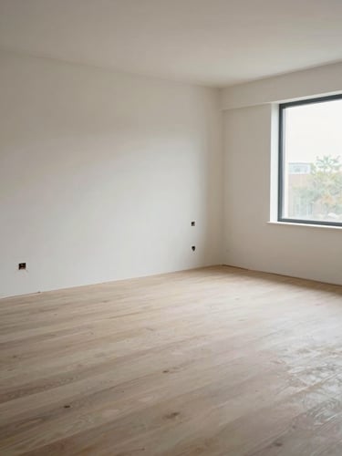 Wide environmental view of a finished interior room at handover — clean floor, no tools remaining, smooth painted walls, natural daylight from a window on the right, empty and orderly