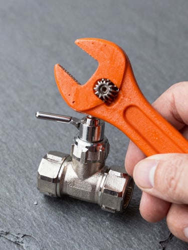 Crisp close-up of a technician's hand adjusting a metallic valve with an orange wrench, bright natural work-light, industrial slate gray background, sharp focus, 35mm