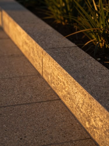 Close-up architectural detail of a manicured limestone pathway and clean garden border, warm golden-hour side lighting, shallow depth of field