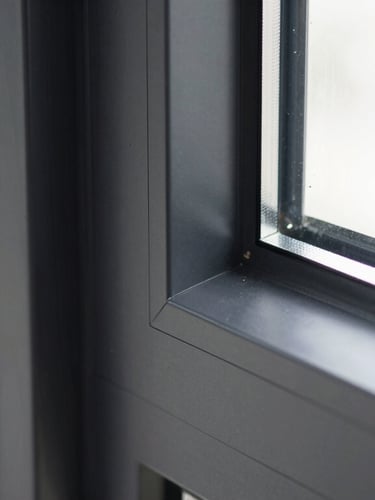 Close-up architectural photography of a black aluminum window frame corner joint, flawless seamless connection, clean lines, bright daylight highlighting the matte texture, sharp shadows, 35mm lens.
