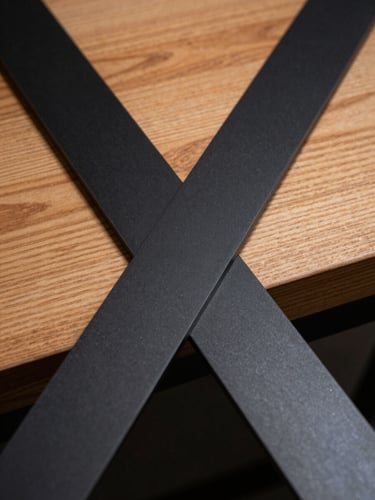 Close-up of matte black steel intersecting with warm timber grain, soft natural light highlighting the texture.