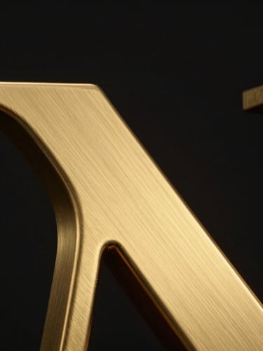 Macro extreme close-up of a premium gold finish 3D letter joint, showing brushed metallic texture and subtle backlighting, high-contrast studio lighting, 35mm