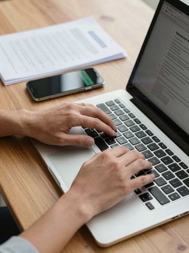 Close-up of hands typing on a laptop next to a smartphone showing a secure chat, organized physical documents with official stamps on a clean wooden desk, bright natural daylight.
