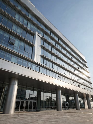 Wide-angle architectural rendering of a modern hospital facade in Baku, sharp glass and silver-metallic panels reflecting cool daylight, high-contrast shadows, expansive negative space.